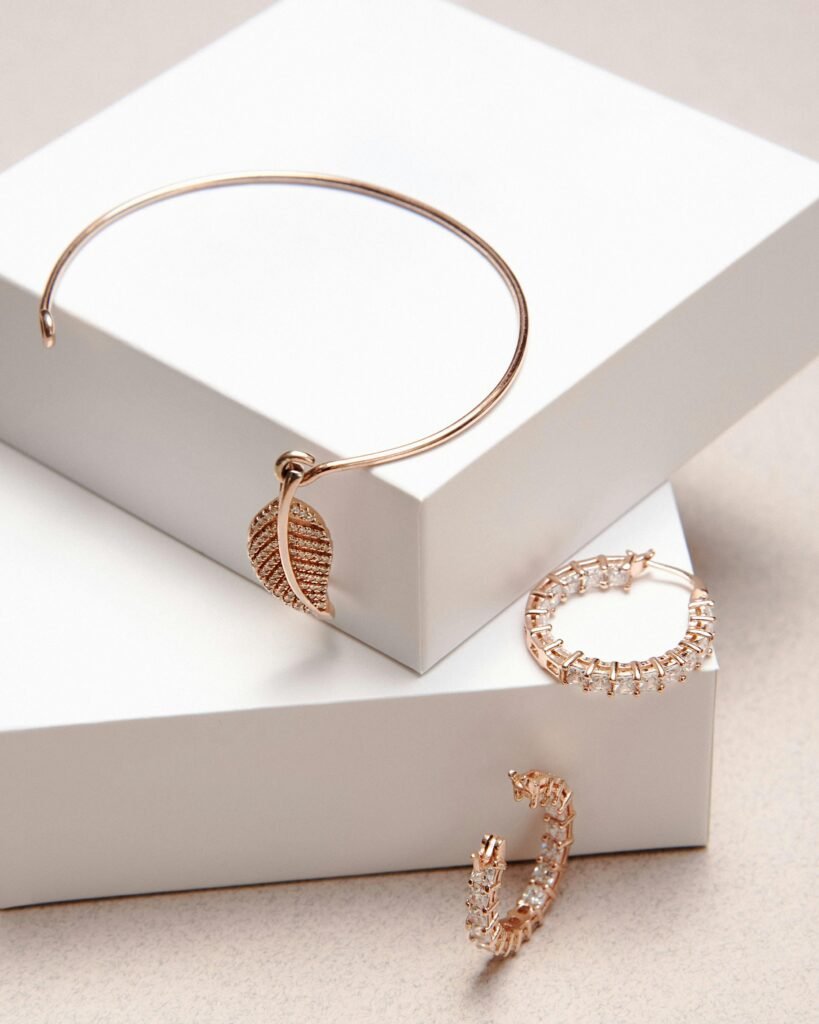Stunning gold jewelry including bracelets and earrings showcased on minimalist white pedestals.